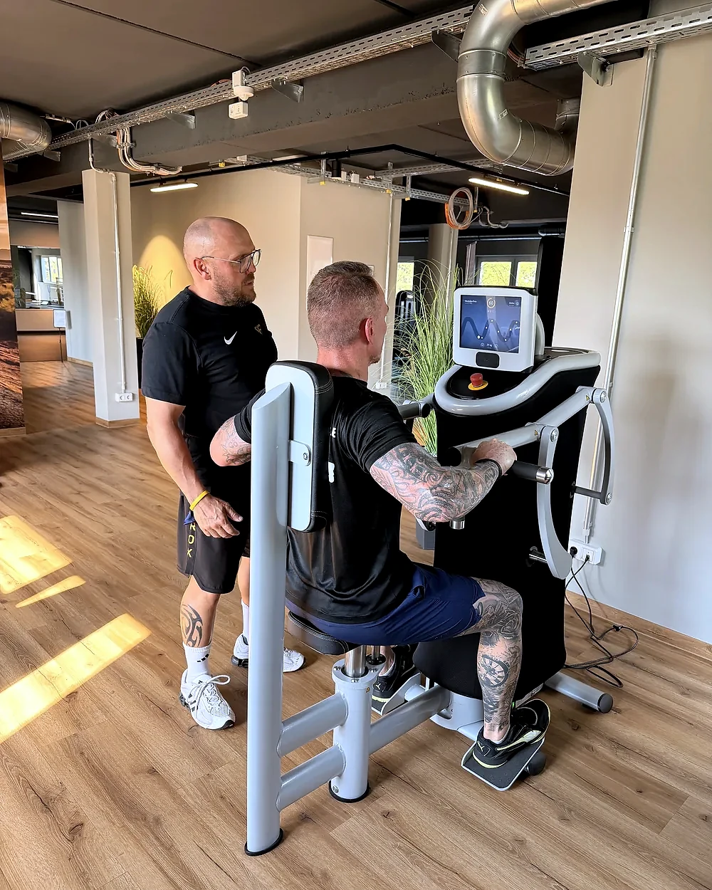 Trainer Mirko begleitet ein Mitglied beim EGYM-Krafttest im Fitnessstudio Hohenstein-Ernstthal – Lila Fitness