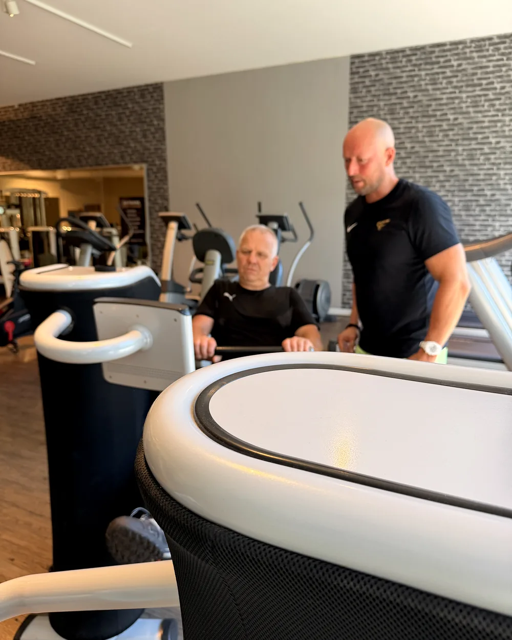 Trainer stimmt das EGYM-Training mit einem Mitglied ab im Fitnessstudio Lichtenstein – Lila Fitness