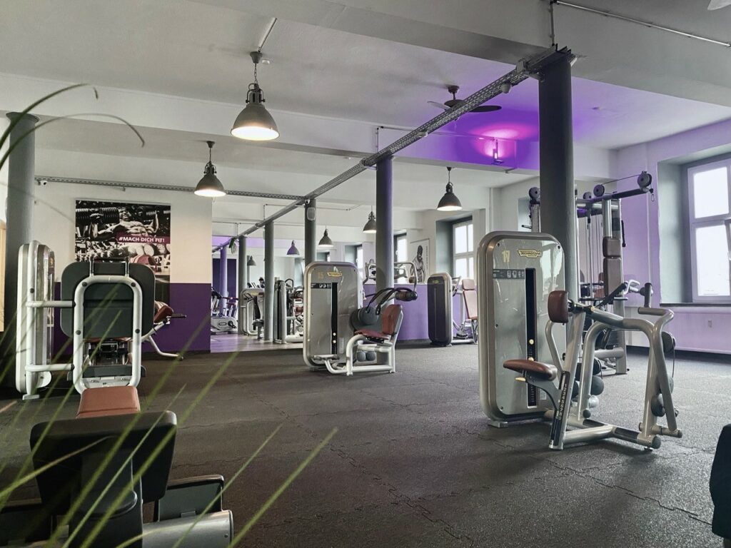Einblick in den Trainingsraum des Lila Fitness Fitnessstudios Flöha mit verschiedenen Sportgeräten links und in der Mitte des Bilder